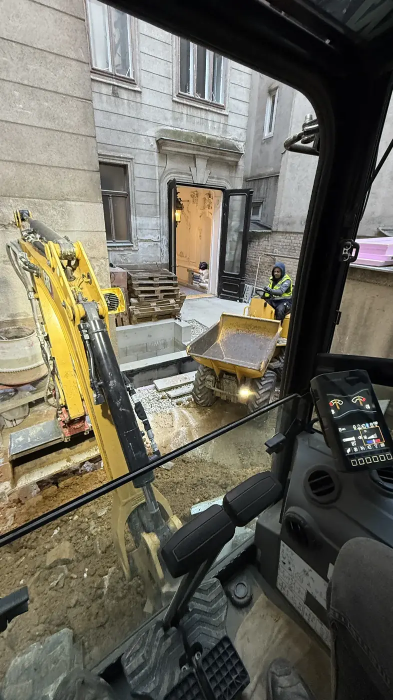 Aushub in einem Innenhof, Blick aus der Fahrerkabine des Minibaggers